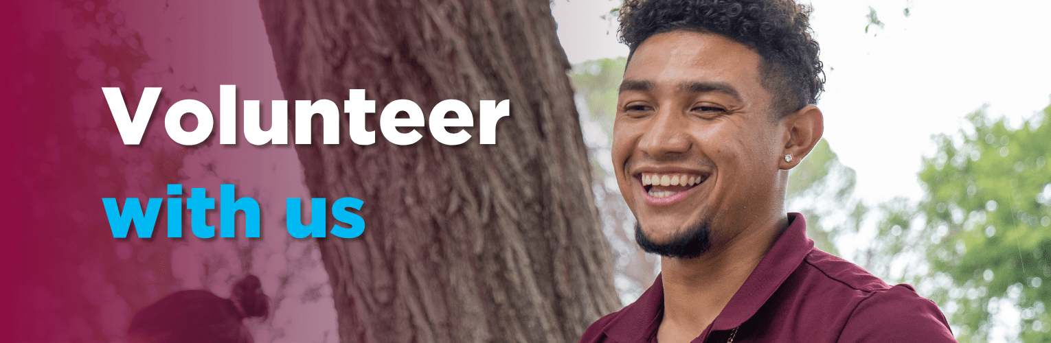 Smiling young man in a maroon shirt volunteers at Pete's Pantry in the Park.